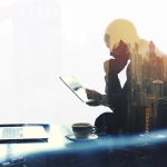 Double exposure silhouette of man reviewing an important message on his tablet and laptop
