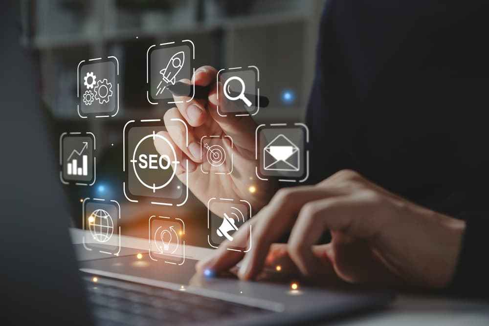 A man's hands working on a laptop overlaid with digital marketing-related icons
