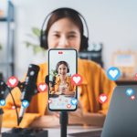 A video content creator livestreaming as heart emojis drift across the screen.