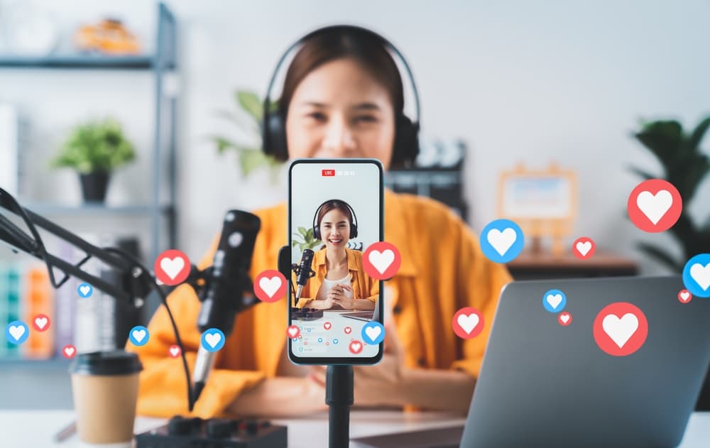 A video content creator livestreaming as heart emojis drift across the screen.