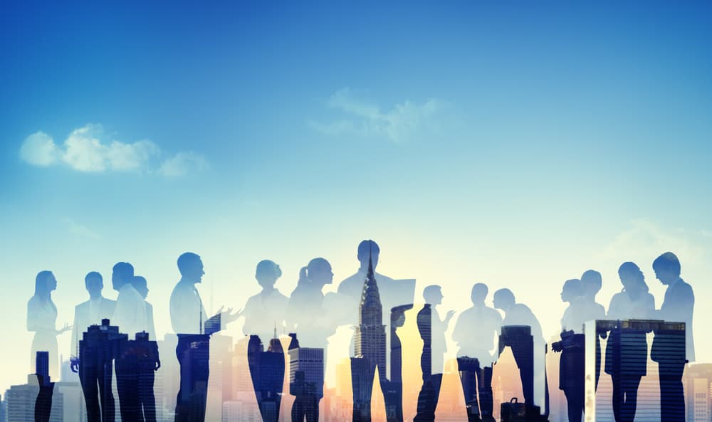 A conceptual image of business people standing silhouetted against a backdrop of New York City at sunrise